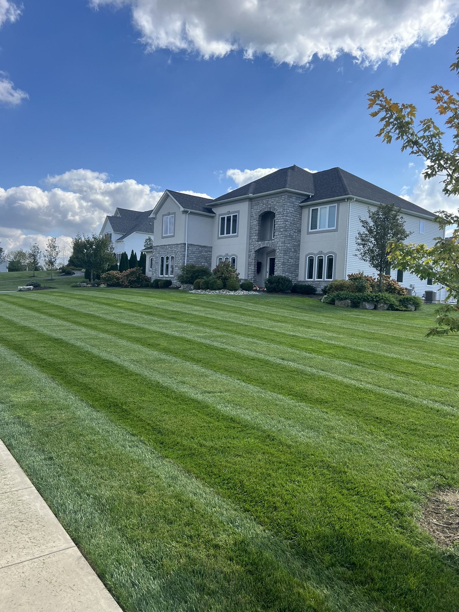 Beautiful striped lawn in front of large stone home
